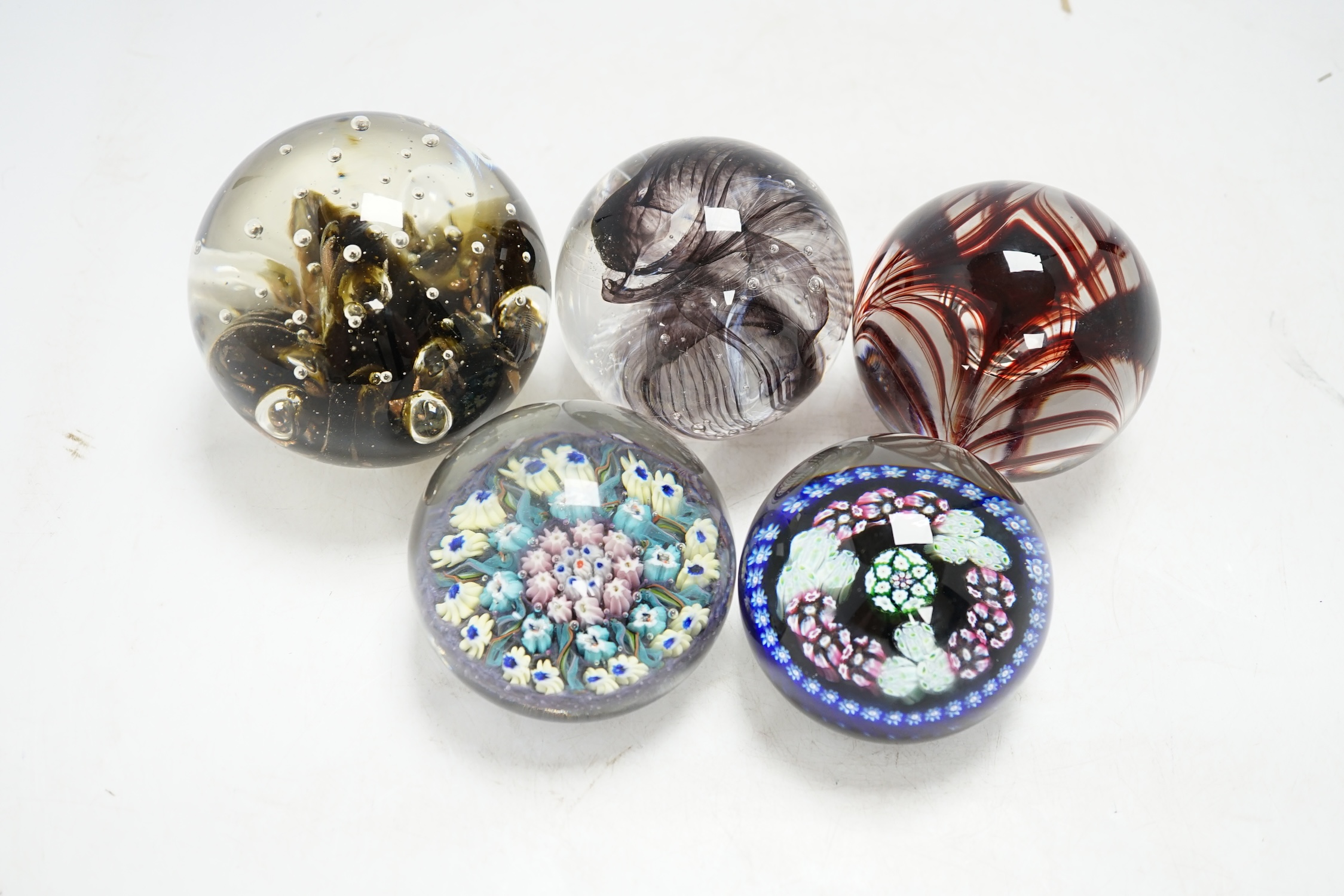 Five glass paperweights to include a Langham Glass House example and two millefiori examples, largest 9cm diameter., Condition - four good, one with impact damage